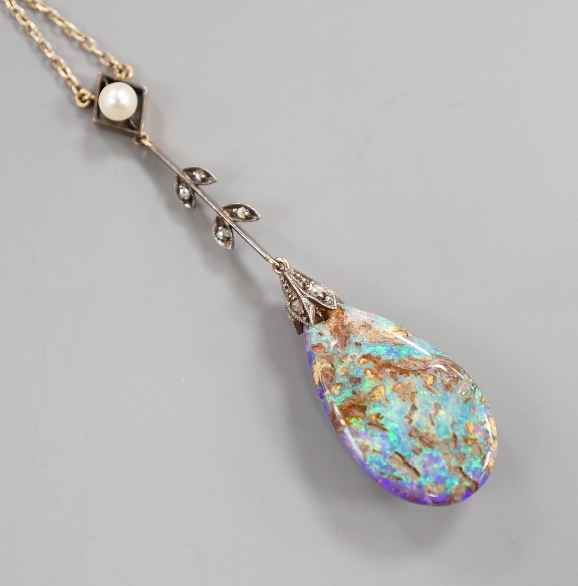 An early 20th century yellow and white metal, pear shaped black opal, rose cut diamond and seed pearl set drop pendant necklace, pendant overall 57mm, chain stamped 9ct, 37cm, gross weight 5.9 grams.